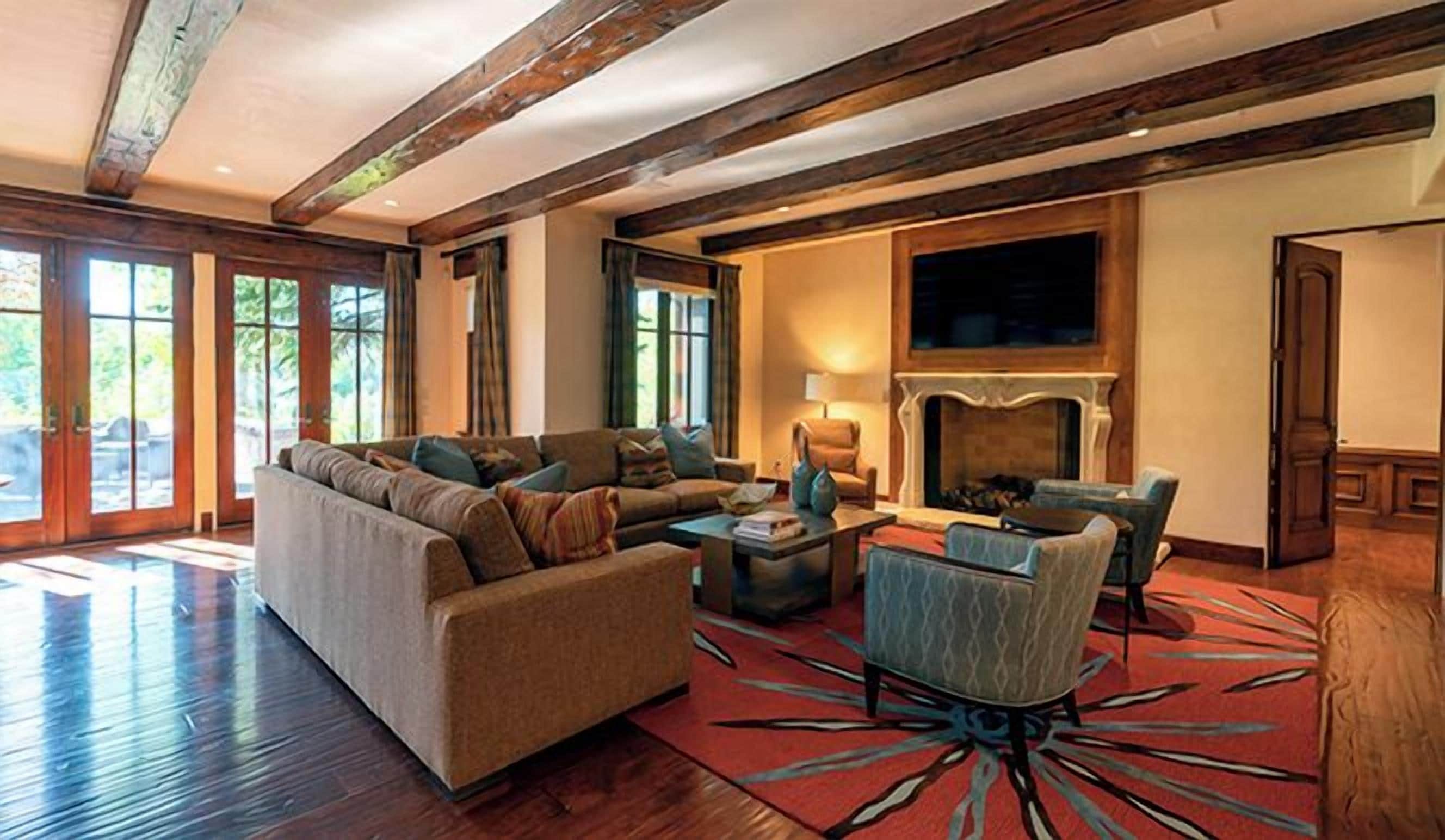 A spacious living room with a large sofa, a smaller armchair, and a fireplace.