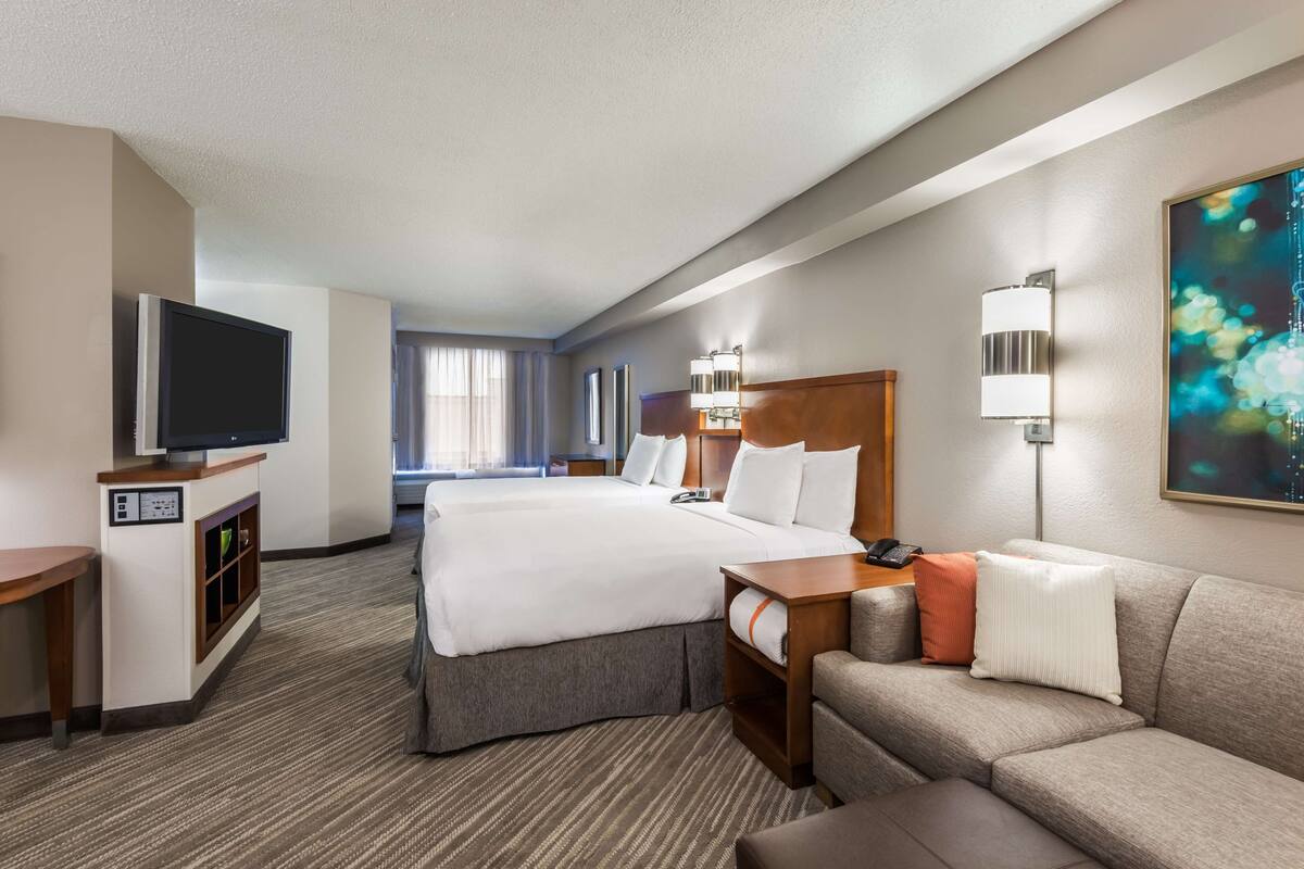 Een hotelkamer met twee bedden, een televisie, een bureau en een bank.