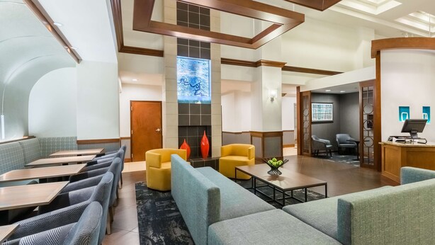 Un moderno vestíbulo de hotel con zonas de estar, una chimenea y un mostrador de recepción.