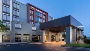 Un hôtel à plusieurs étages, reconnaissable à son grand panneau « Hyatt Place », doté d’une entrée abritée et d’un parking.