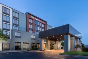 Een meerlaags hotel met een opvallend 'Hyatt Place' bord, een overdekte ingang en een parkeerplaats.