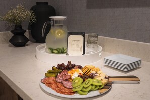 Een buffet met diverse gerechten, waaronder vleeswaren, kazen en fruit.