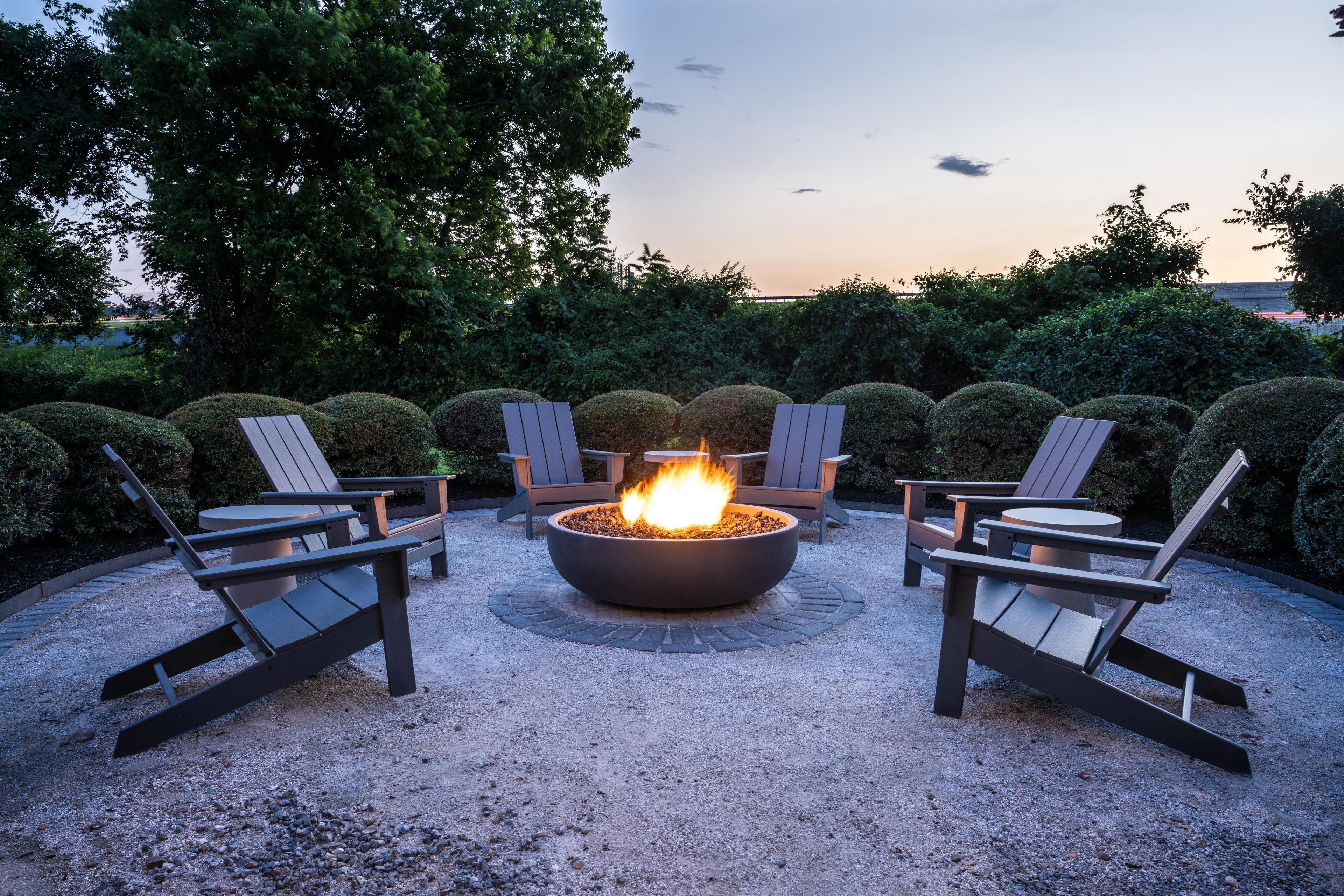 Een vuurplaats omringd door Adirondack-stoelen in een openlucht omgeving.
