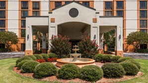 A Hyatt Place hotel with a central fountain, surrounded by well-manicured bushes and flowers.