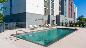 Un hôtel doté d’une piscine, de chaises longues et d’une entrée sécurisée par un portail.