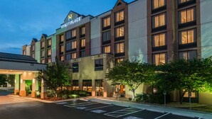Un hotel de varios pisos con un llamativo letrero de 'Hyatt Place', un acceso cubierto y un estacionamiento con espacios para discapacitados.