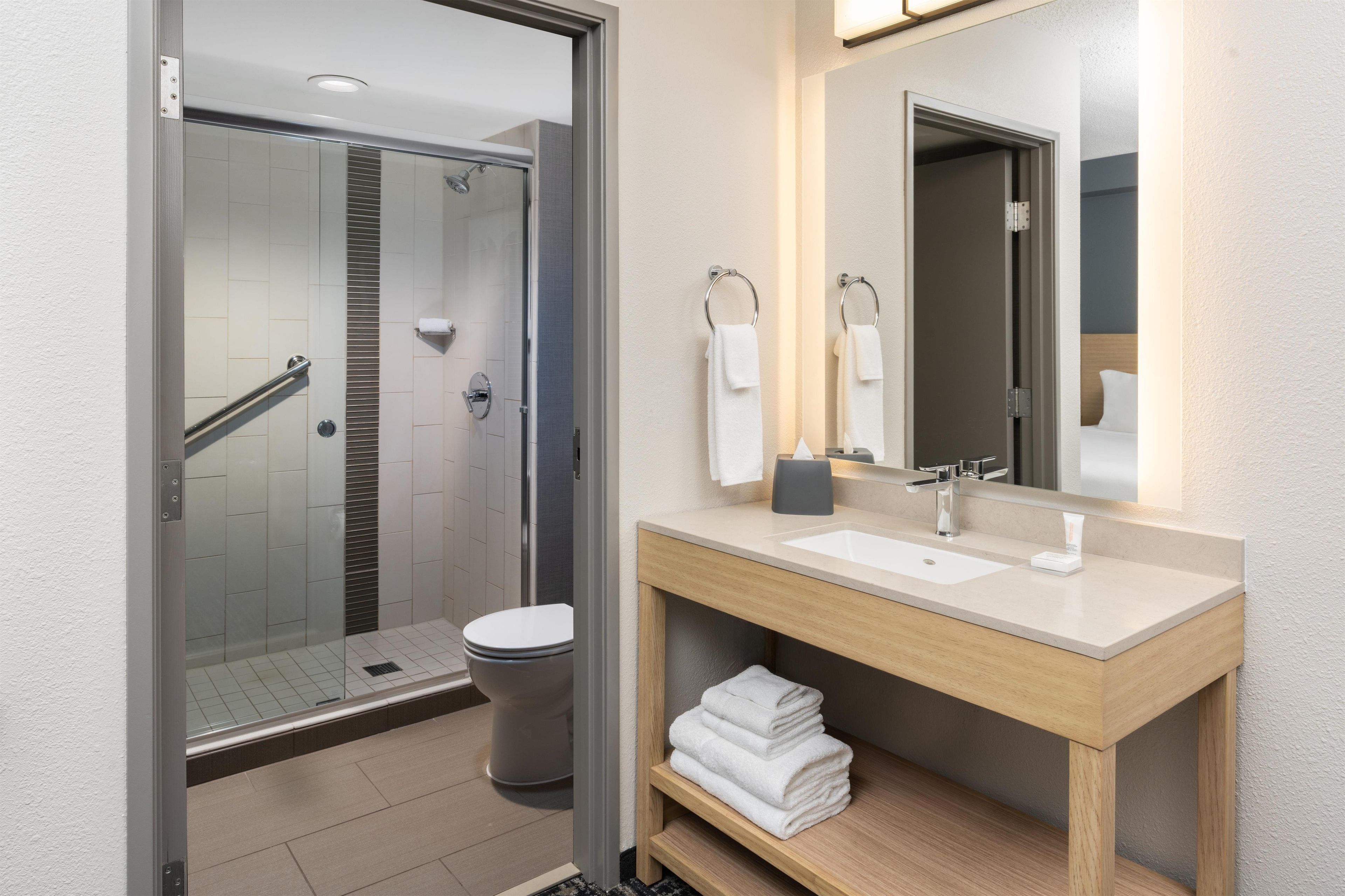 Un bagno moderno con box doccia in vetro, un water, un lavandino con specchio e un porta asciugamani.