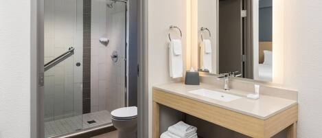 Un bagno moderno con box doccia in vetro, un water, un lavandino con specchio e un porta asciugamani.