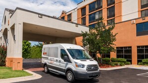 A white van parked in front of a Hyatt Place hotel with a modern architectural design.