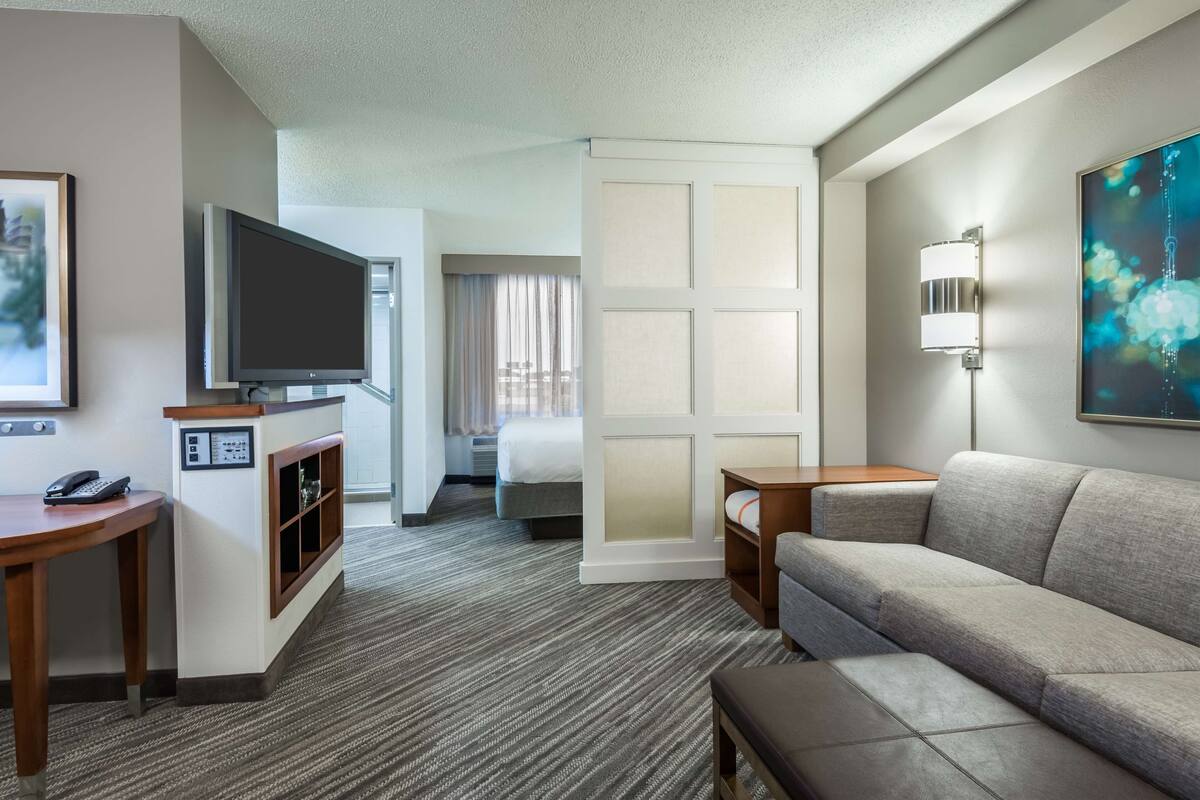 Hotelkamer met flatscreen televisie, een bank, een klein tafeltje, een bureau en een bed met uitzicht op de stad.