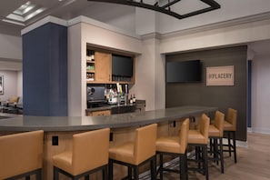 A bar area with a long counter, multiple bar stools, and a television mounted on the wall. - Hyatt Place Bentonville/Rogers (Rogers)