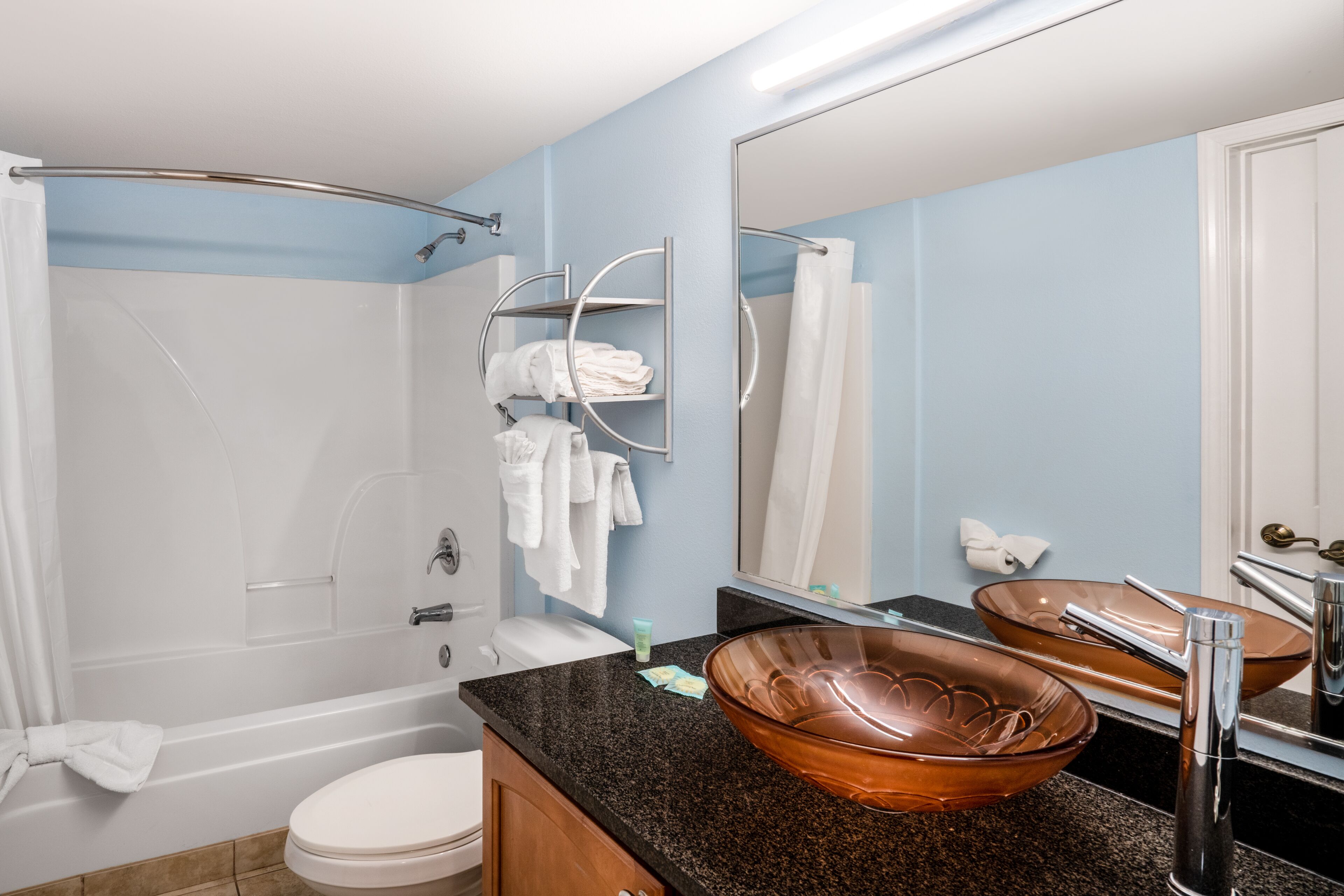 A bathroom with a bathtub, toilet, and a large copper basin on the vanity.