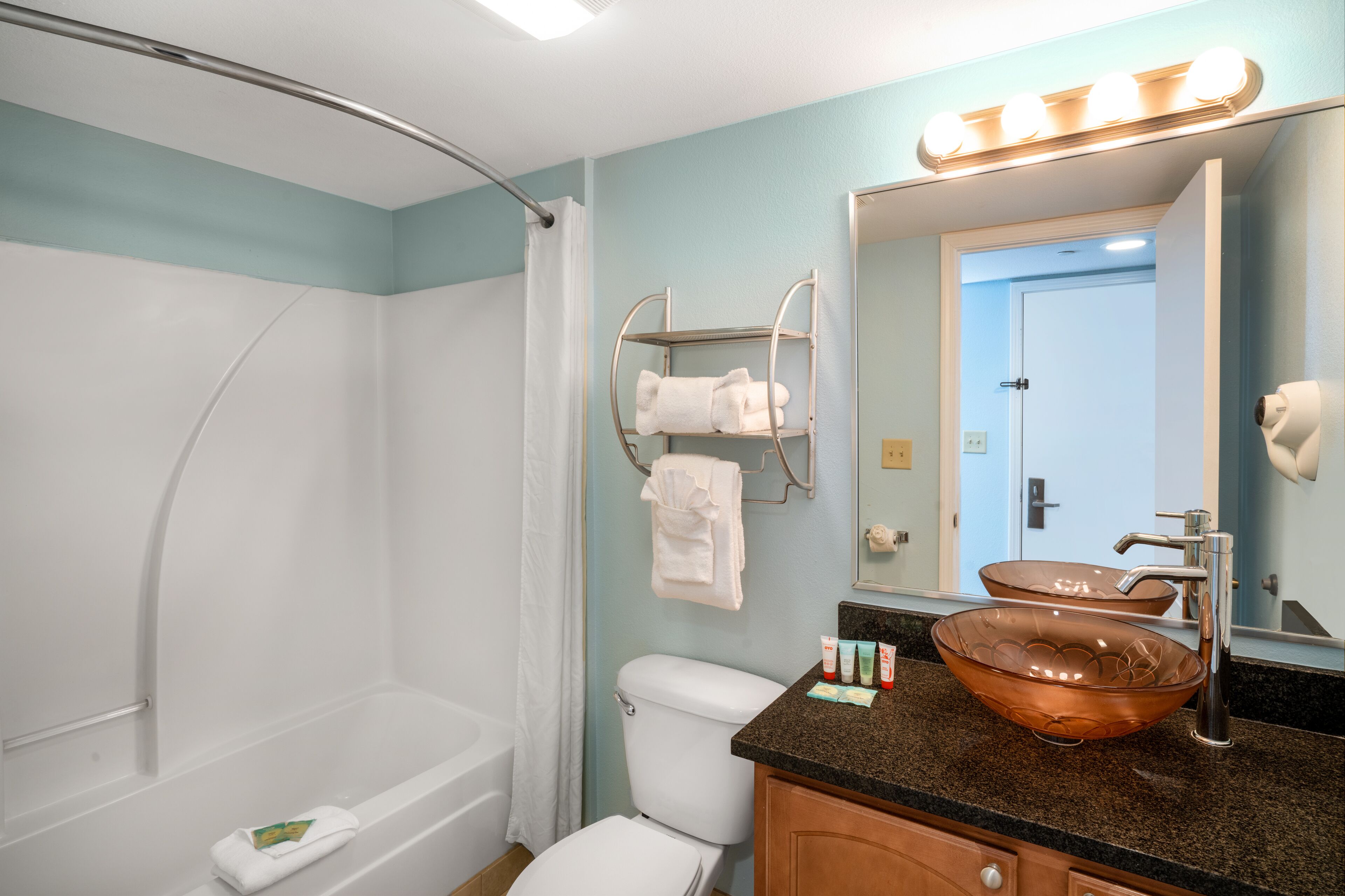 A bathroom with a bathtub, toilet, and a sink with a large mirror.