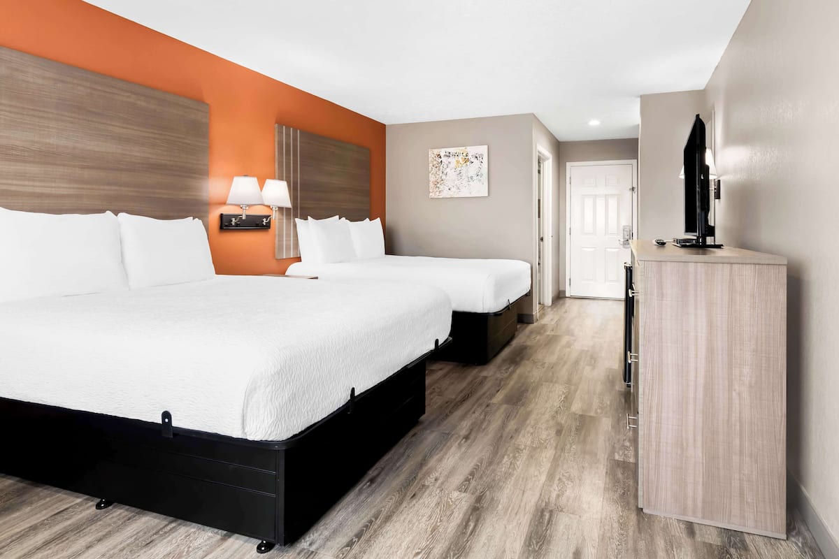 A hotel room with two beds, a desk, and a wardrobe.