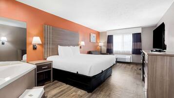 A hotel room with a large bed, bedside tables with lamps, a TV, and a desk area.