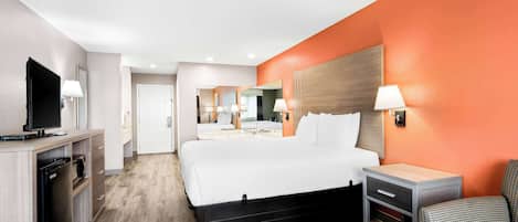Una habitación de hotel con cama, mesita de noche, lámpara y televisor sobre un mueble.