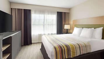 Una habitación de hotel con cama, televisión, escritorio y ventana con cortinas.