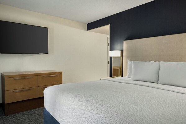 A modern hotel room with a large bed, a wooden dresser, and a flat-screen TV mounted on the wall. - Courtyard by Marriott Richmond Chester (Chester)