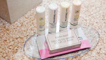 Een glazen dienblad met diverse verzorgingsproducten, zoals douchegel, shampoo en bodylotion.