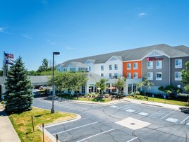 A hotel with a modern design, featuring a mix of white and orange buildings, a parking lot, and a flagpole with an American flag.