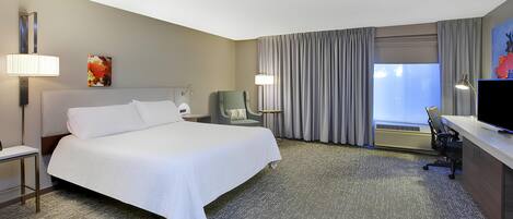 Une chambre d’hôtel avec un grand lit, un bureau équipé d’un ordinateur, une chaise et un téléviseur.
