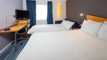 Une chambre d’hôtel avec deux lits, un bureau avec un ordinateur, une télévision et une lampe.
