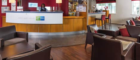 A Holiday Inn Express lobby with a reception desk, seating area, and a bar.