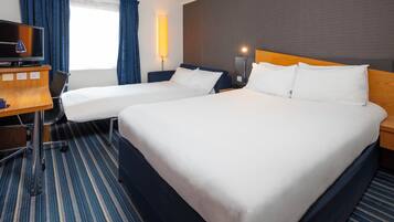 A hotel room with two beds, a desk, a television, and a lamp.