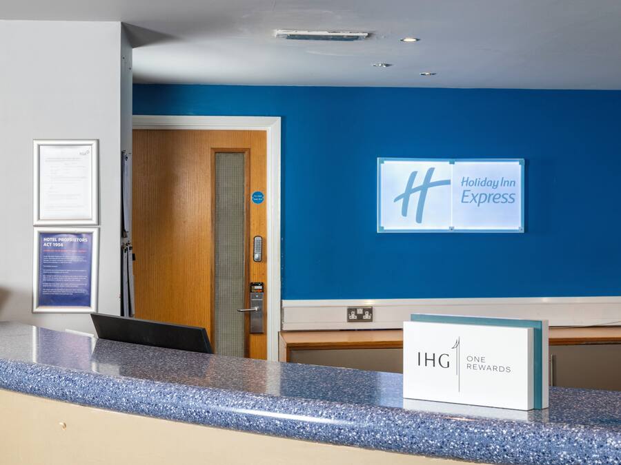 A hotel reception desk with a blue wall, a wooden door, and a sign for Holiday Inn Express.