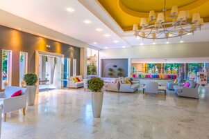 Un vestíbulo amplio con muebles modernos, un gran candelabro y un mural colorido.