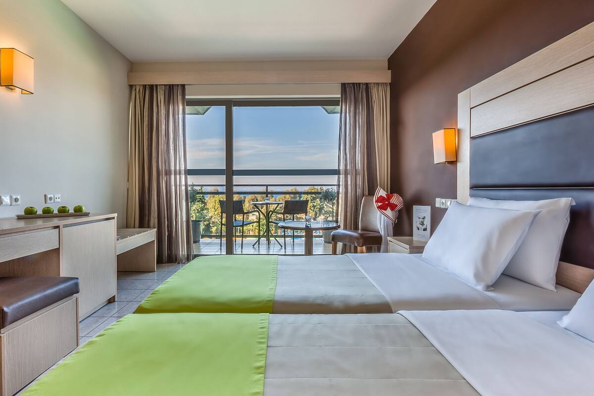 Habitación de hotel con cama, escritorio, silla y vistas al exterior.