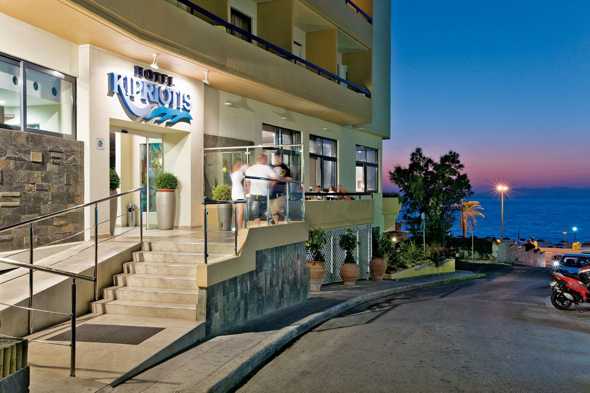 A hotel with a prominent sign, a staircase leading to the entrance, and a view of the ocean at dusk.