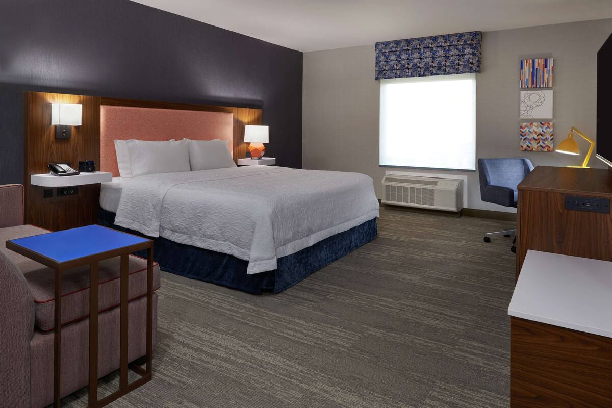 Une chambre d’hôtel avec un grand lit, des tables de chevet, un bureau et une chaise.