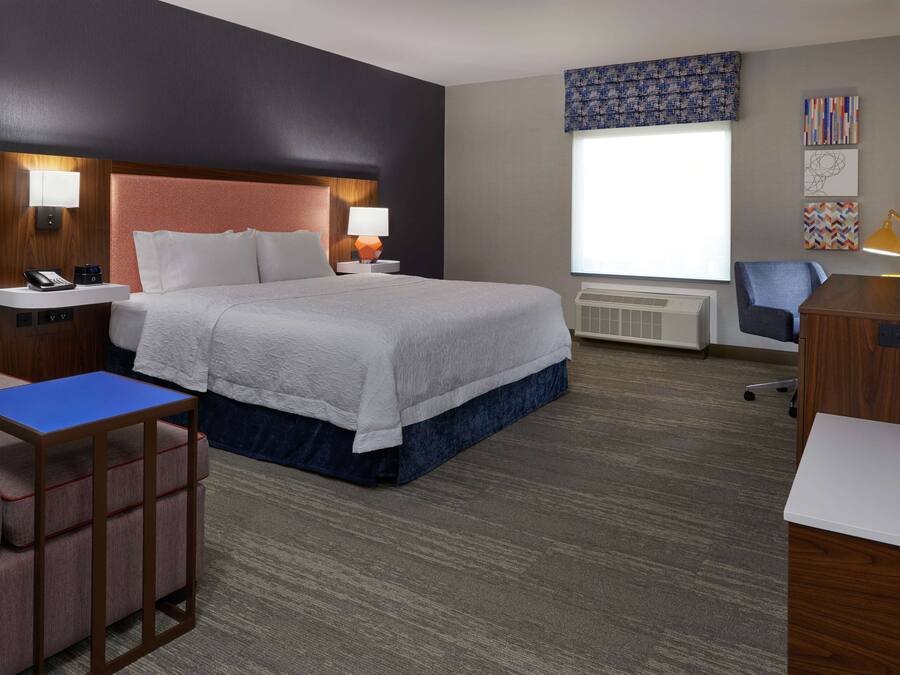 A hotel room with a large bed, bedside tables, a desk, and a chair.