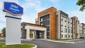 A modern hotel with a prominent sign, a covered entrance, and a parking lot. - Hampton Inn & Suites by Hilton Montreal-Dorval (Dorval)