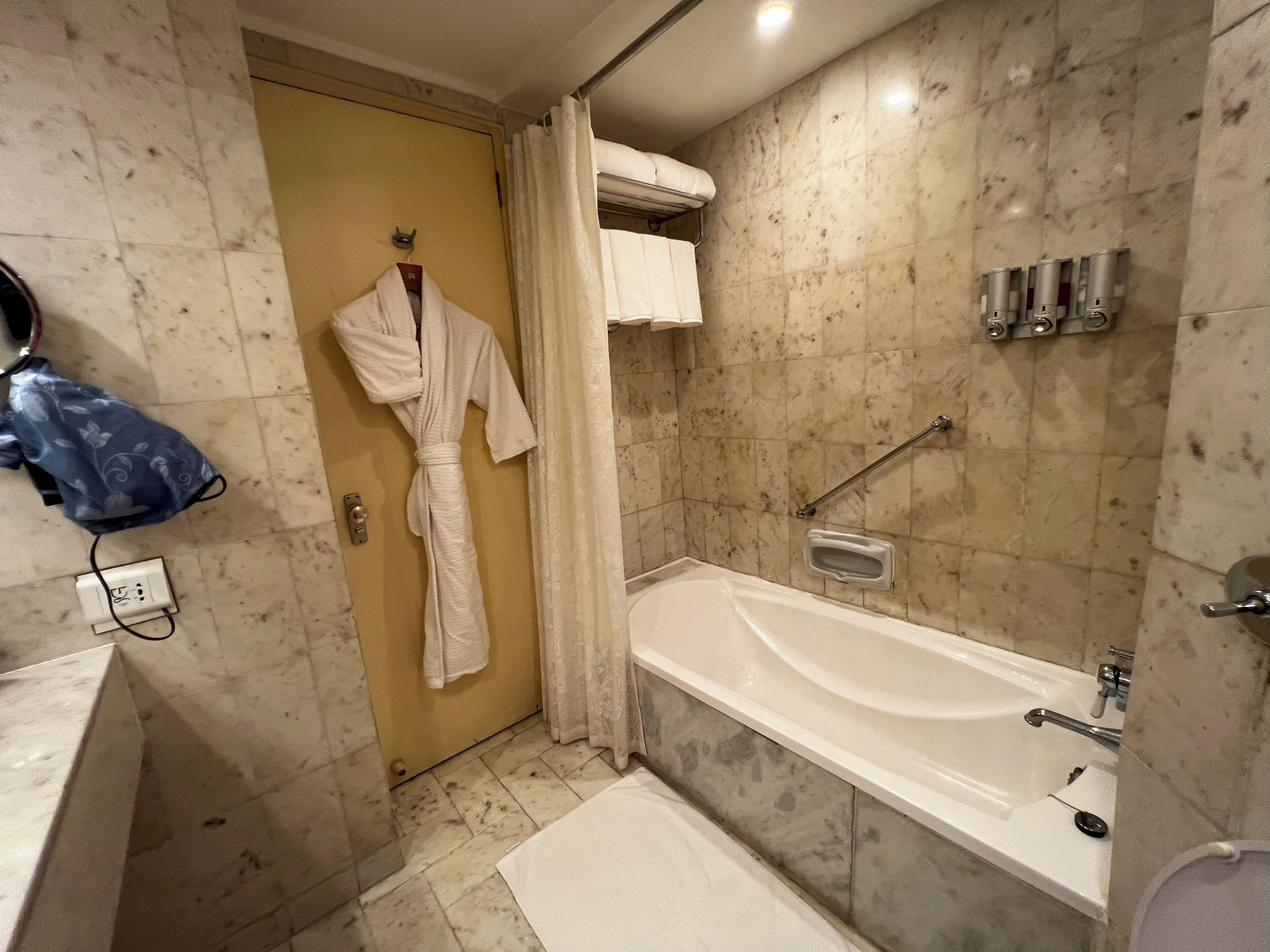 A bathroom with a bathtub, a shower area, and a towel rack with a robe.