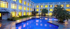 Un hôtel doté d’une piscine, de plusieurs balcons et d’une cour intérieure agrémentée de palmiers.