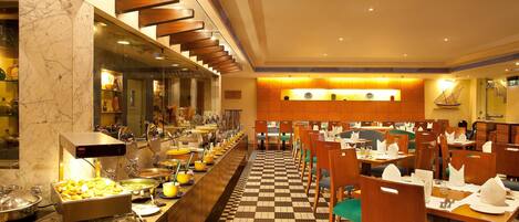A buffet setup with a variety of food items and a checkered floor pattern.