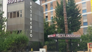 Un hotel anomenat HOTEL DESIDERIO, amb una façana moderna i una entrada tancada per una reixa.