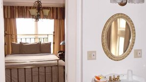 A hotel room with a bed, a mirror, a sink, and a trash bin. - Van Gilder Hotel (Seward)