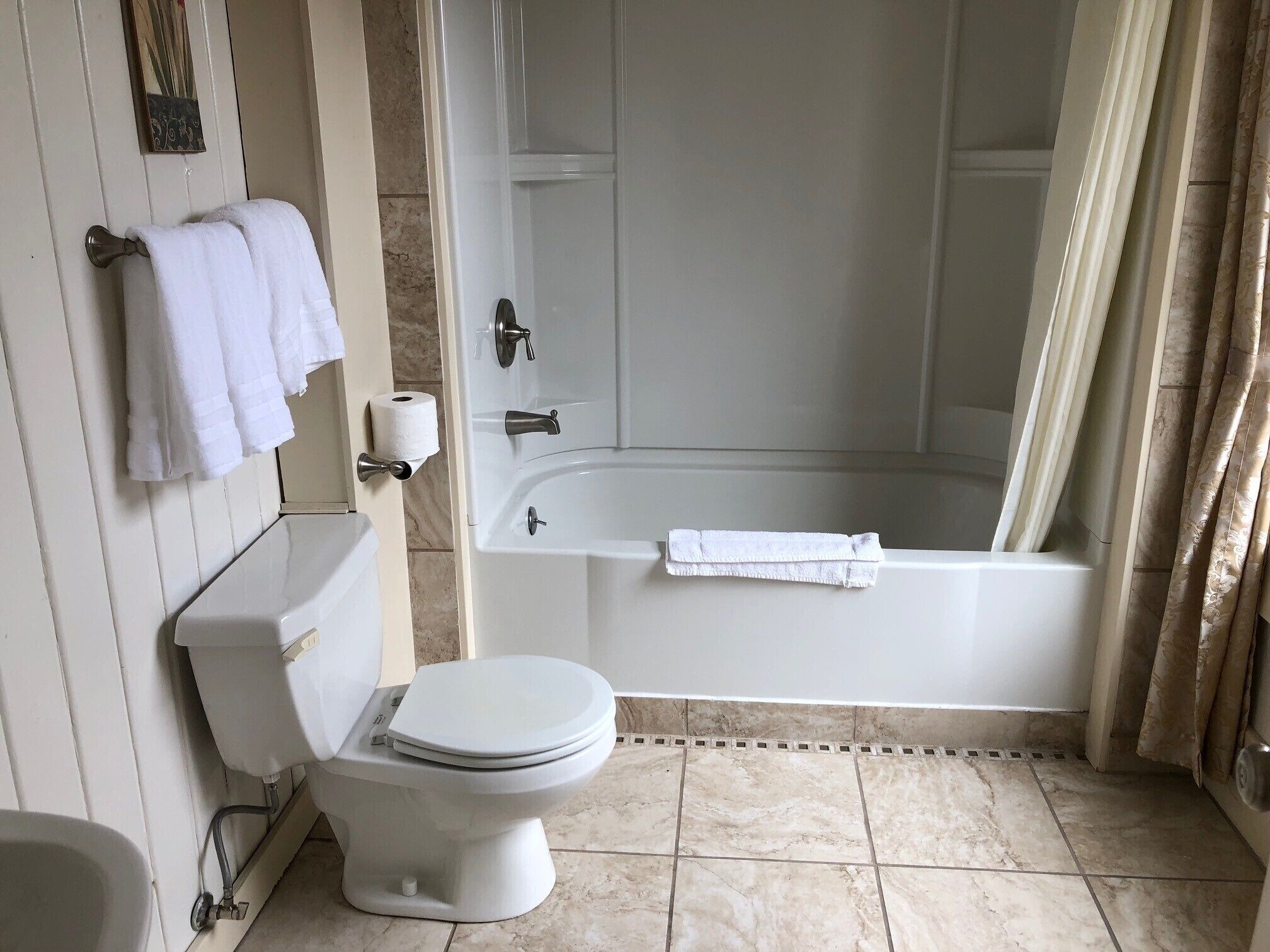 A bathroom with a toilet, a sink, a bathtub, and a shower curtain.