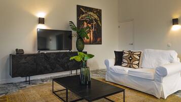 Una sala de estar moderna con una mesa de centro negra, un sofá blanco, un mueble negro y un televisor en la pared.
