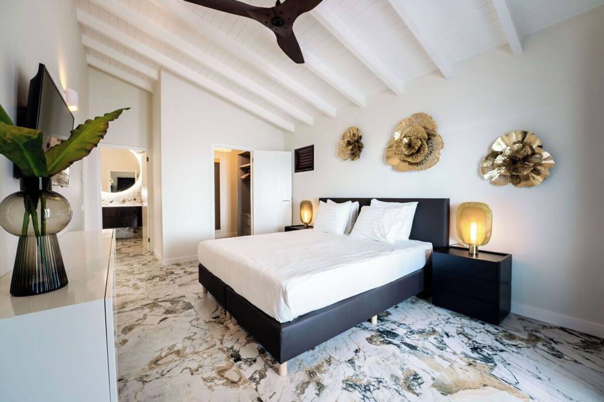 Un dormitorio con una cama grande, una mesita de noche con lámpara y decoración en la pared.