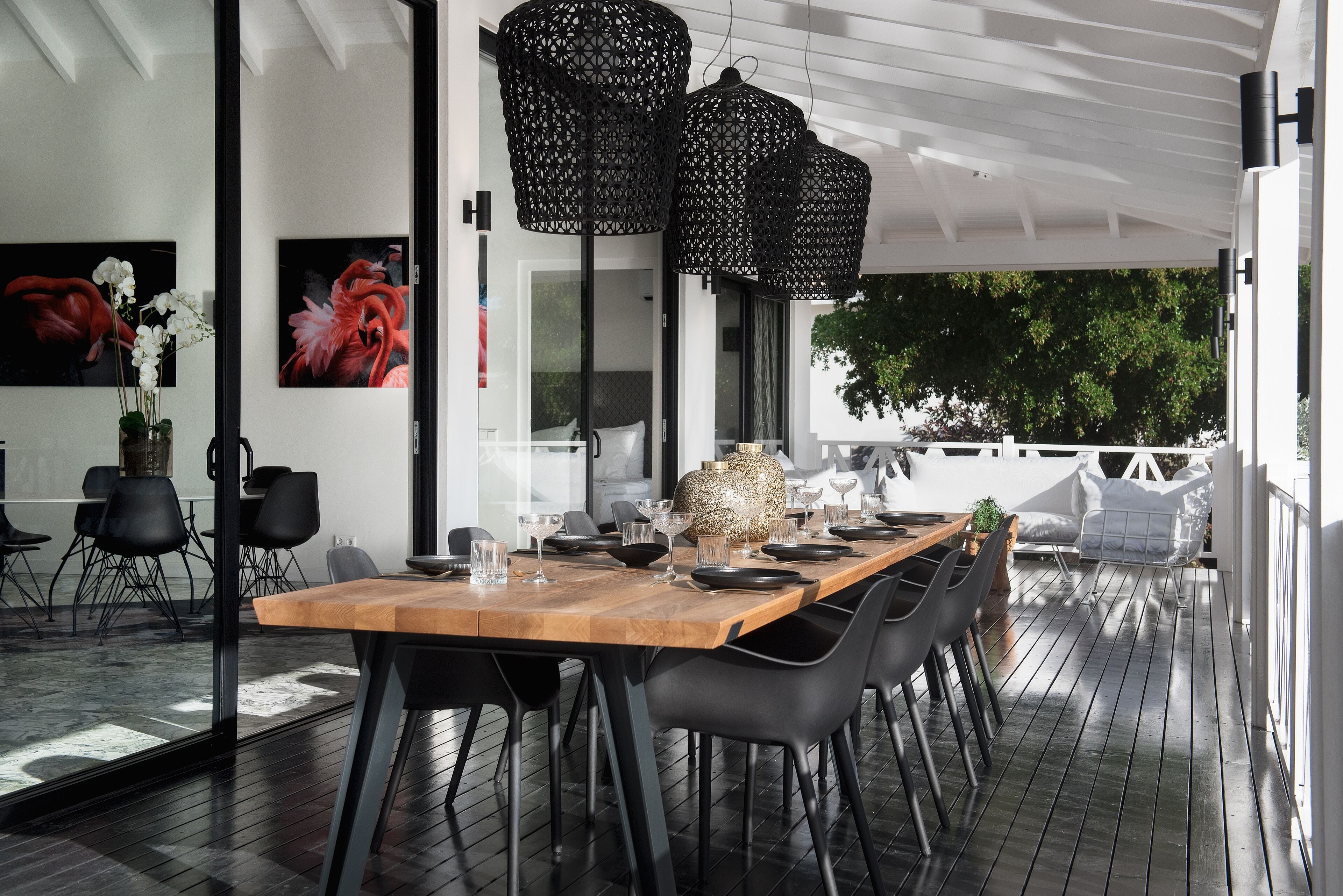 An outdoor dining area with a wooden table, black chairs, and black hanging lanterns.