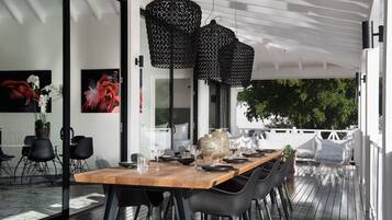 An outdoor dining area with a wooden table, black chairs, and black hanging lanterns.