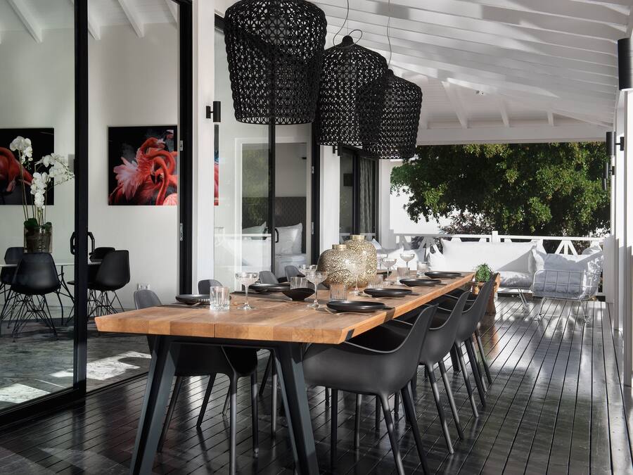 An outdoor dining area with a wooden table, black chairs, and black hanging lanterns.