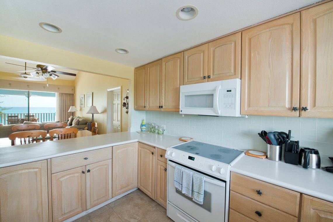 A kitchen with wooden cabinets, a microwave, a stove, and a dining area with a table and chairs.