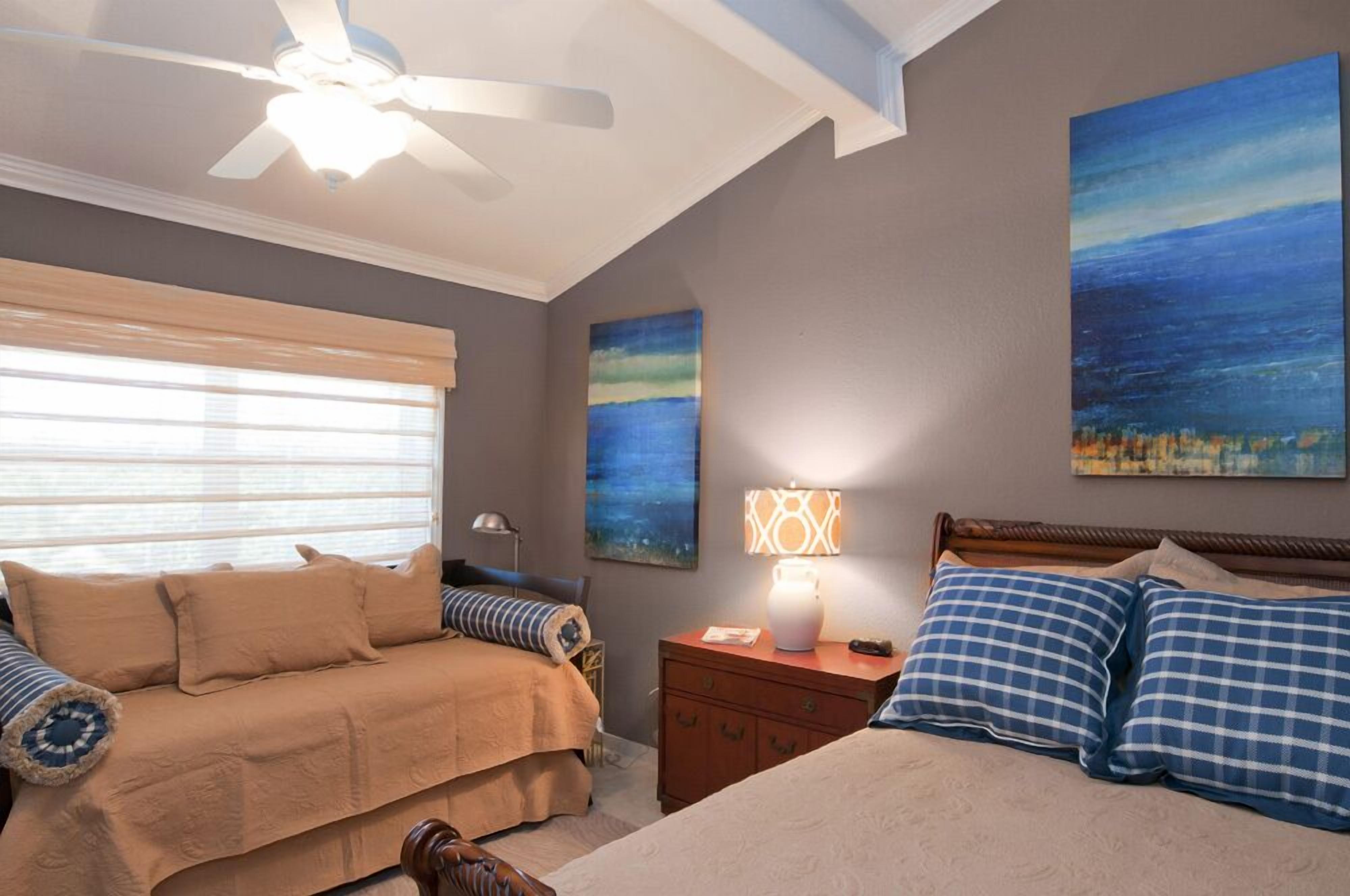 A bedroom with a bed, a nightstand, a lamp, and two paintings on the wall.