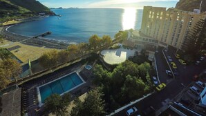Un hotel frente al mar con piscina, estacionamiento y vistas al océano.