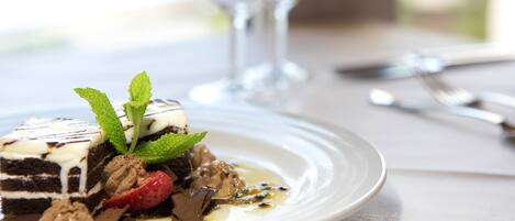 A dessert on a plate with a glass and cutlery on a table.